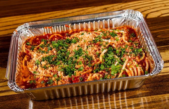Spaghetti with red sauce, cheese, and herbs in a San Diego’s Best Pizza takeout container.